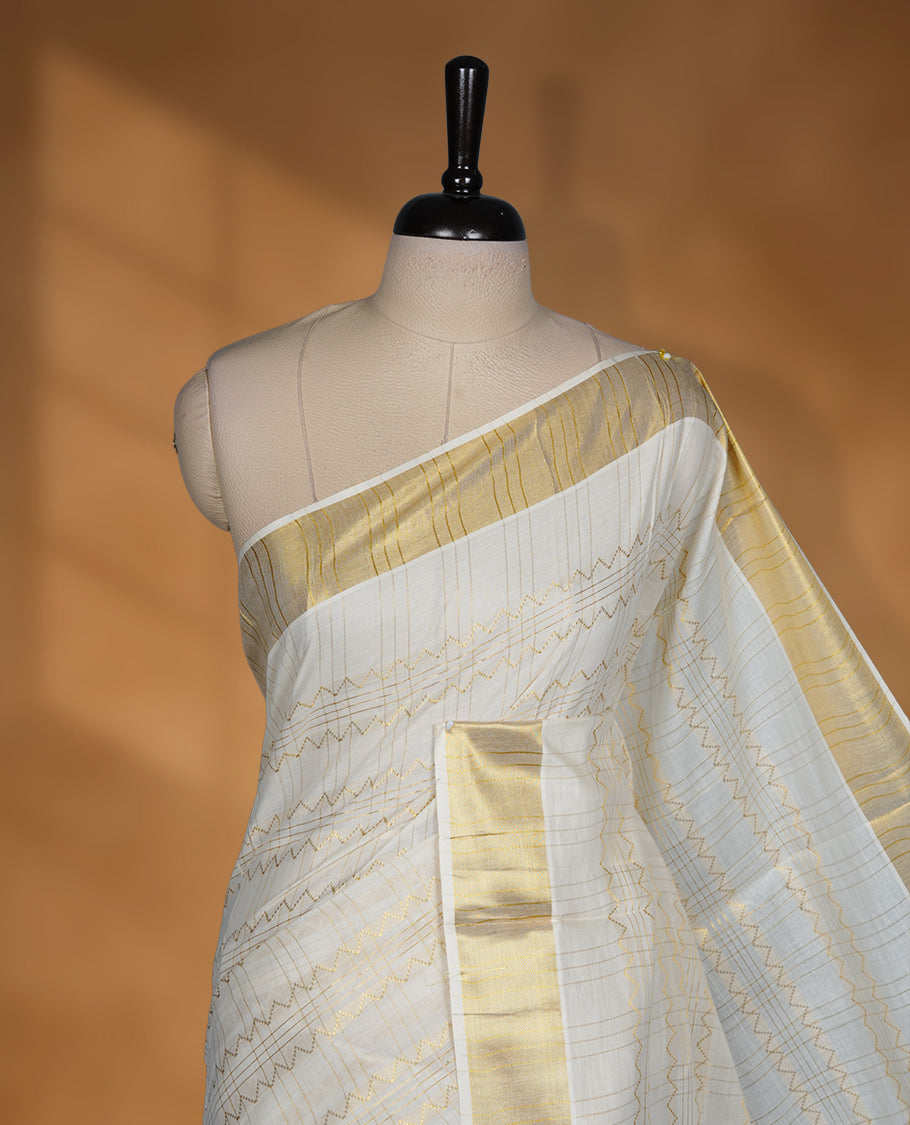 Off white Cotton Kerala saree featuring a subtle zari patterned body, complemented by a classic golden zari border and traditional pallu, paired with a matching blouse.
