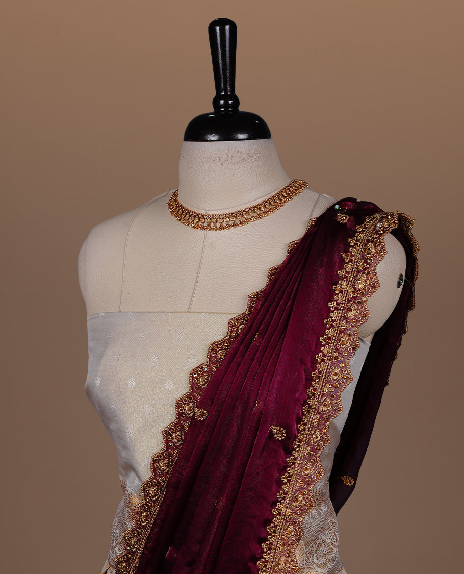 Light gold colour semi banaras semi stitched dhavani set featuring gold zari floral kodi motifs and traditional border, unstitched matching blouse piece and contrast Maroon colour Duptta with gold thread and beats worked border.