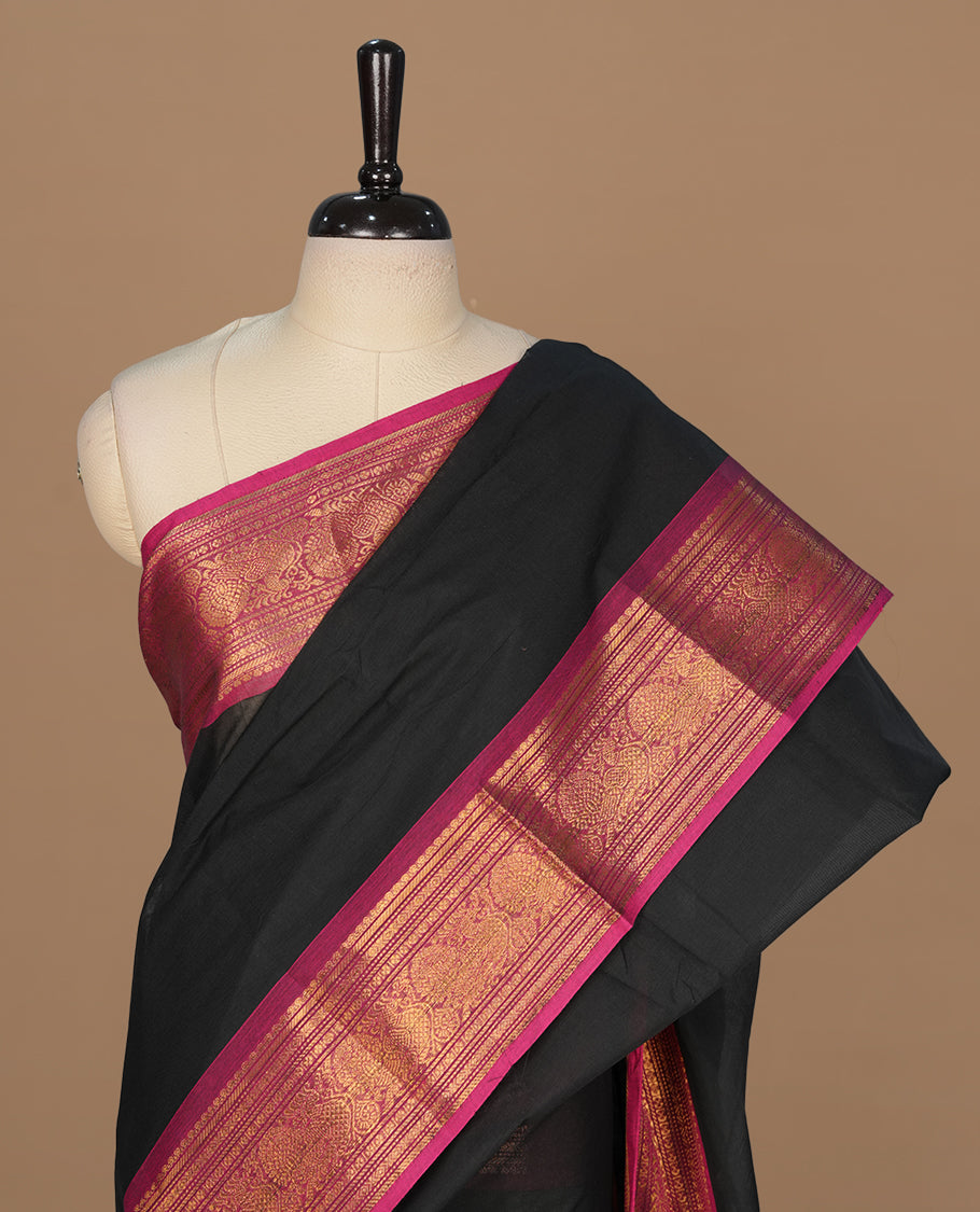 Black colour chettinad cotton saree featuring elegant plain body, complemented by contrast magenta colour with gold zari border, paired with matching blouse piece.