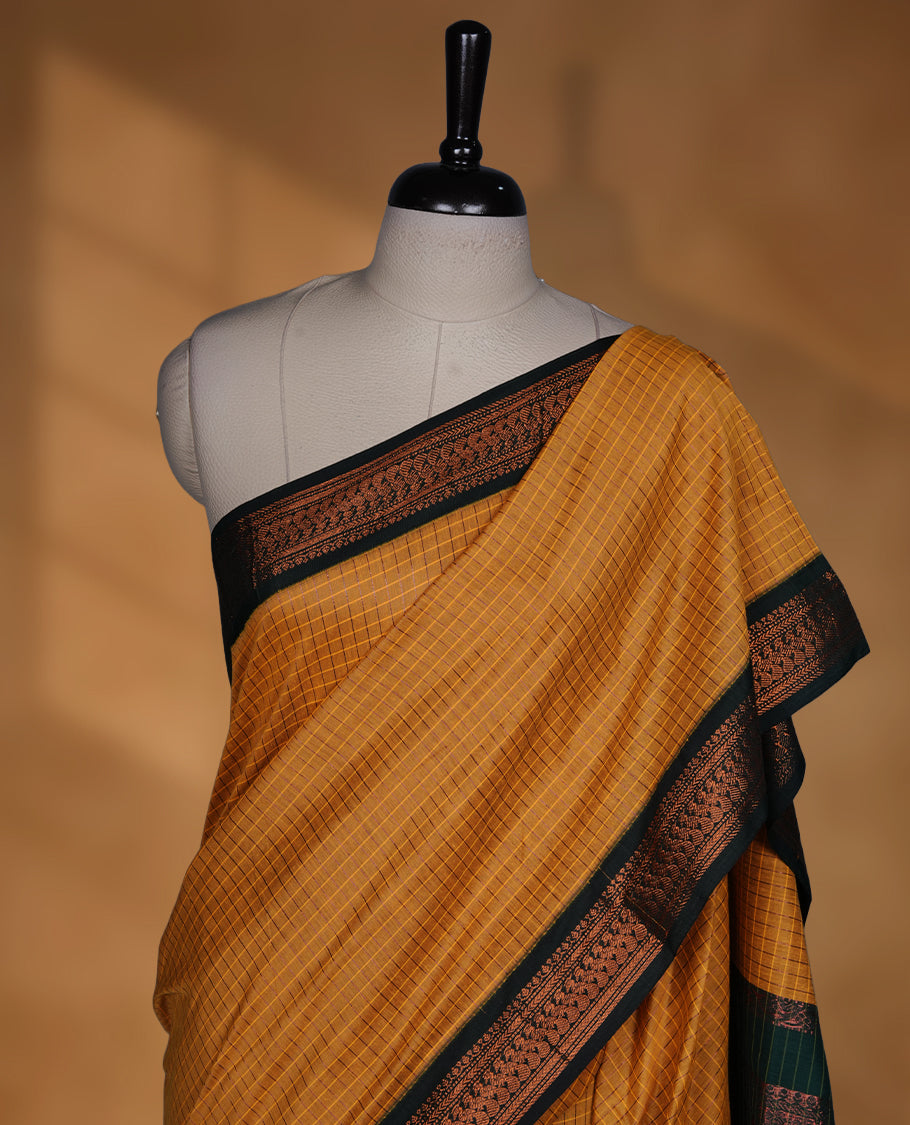 Mustard yellow colour mixed kalyani cotton saree featuring fine checked body, complemented by a dark green zari border and richly woven traditional pallu, paired with a matching blouse.