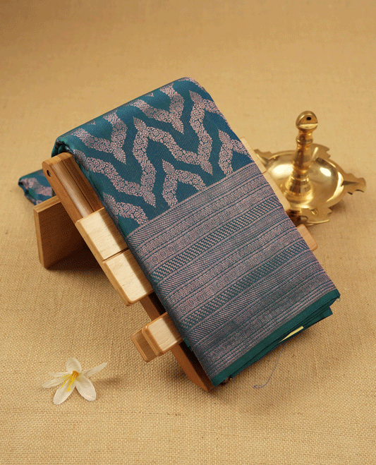 Peacock Blue Colour Manthrakodi saree featuring an antique zari Banarasi design on the body, complemented by a self coloured traditional border and a matching self coloured blouse.