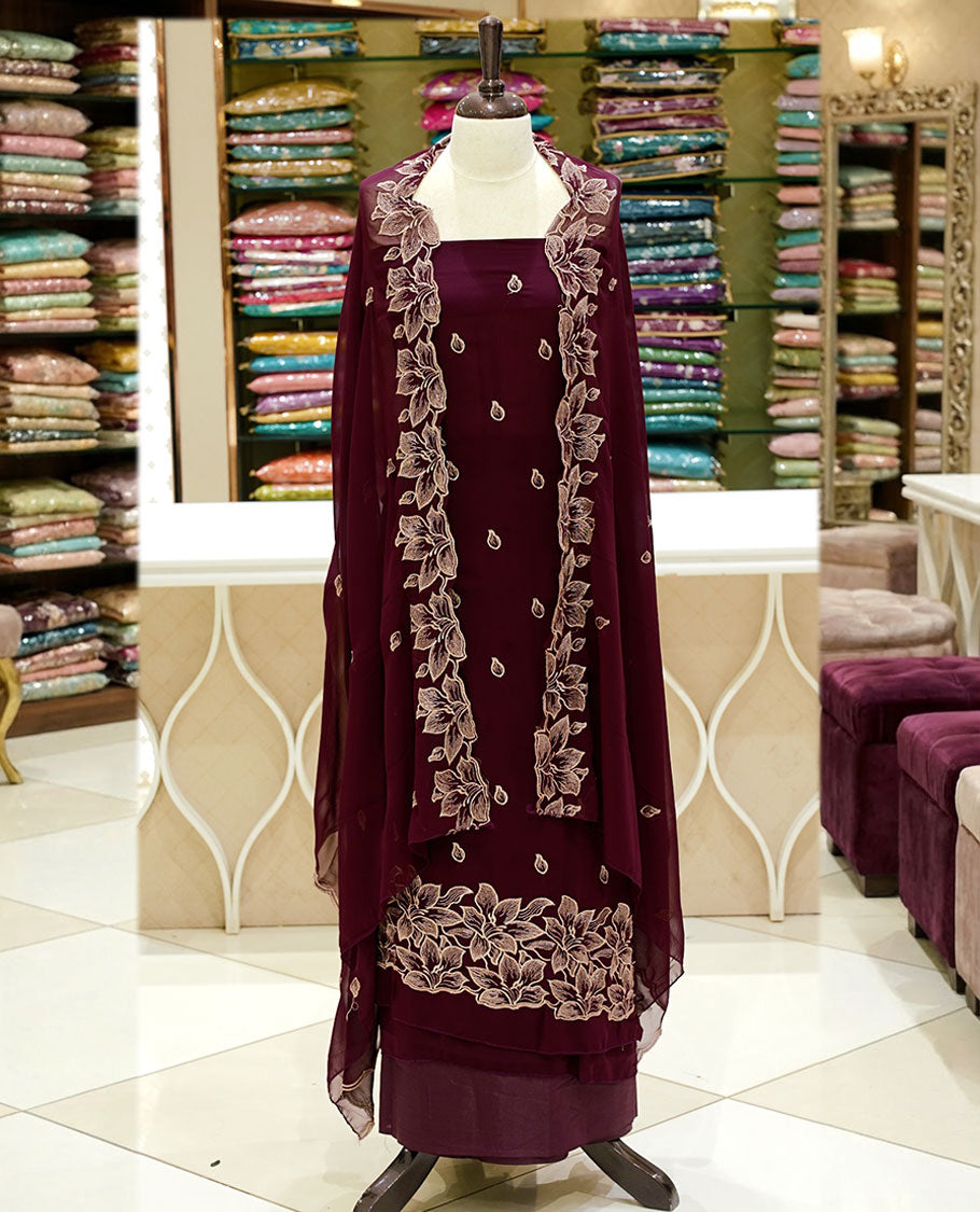 Burgundy colour georgette salwar set featuring gold zari buttas on body, floral embroidery and scalp work on dupatta, paired with matching bottom.