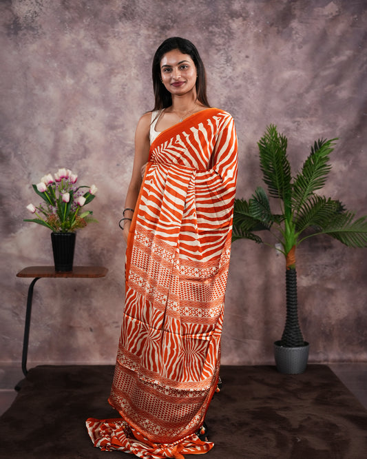 Orange Colour satin model saree featuring Zibra print on body. Ajrak & zibra print on pallu with jhumka tassels, comes with contrast plain blouse piece.