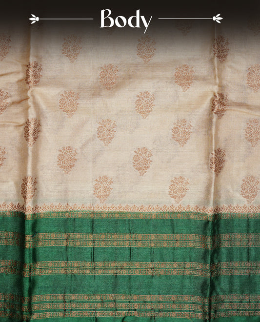 Golden Cream Colour Banaras tussar silk saree featuring Antique zari Motifs on body, Complemented by green colour variant with zari border, paired with matching blouse Piece.