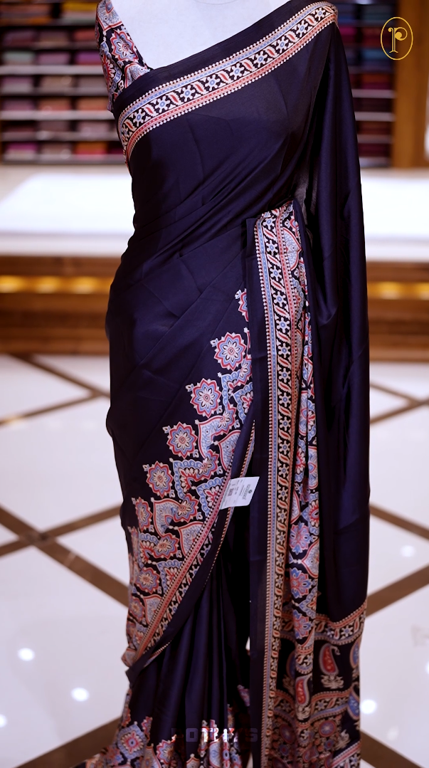 Black Semi modal silk saree featuring traditional Ajrakh print with intricate motifs and contrast borders, paired with a perfectly matching blouse & A timeless piece blending heritage with grace.