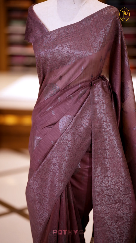 Brown colour semi silk saree with a stunning silver thread border and intricate leaf design & Comes with a perfectly matching blouse piece, ideal for festive and formal occasions.
