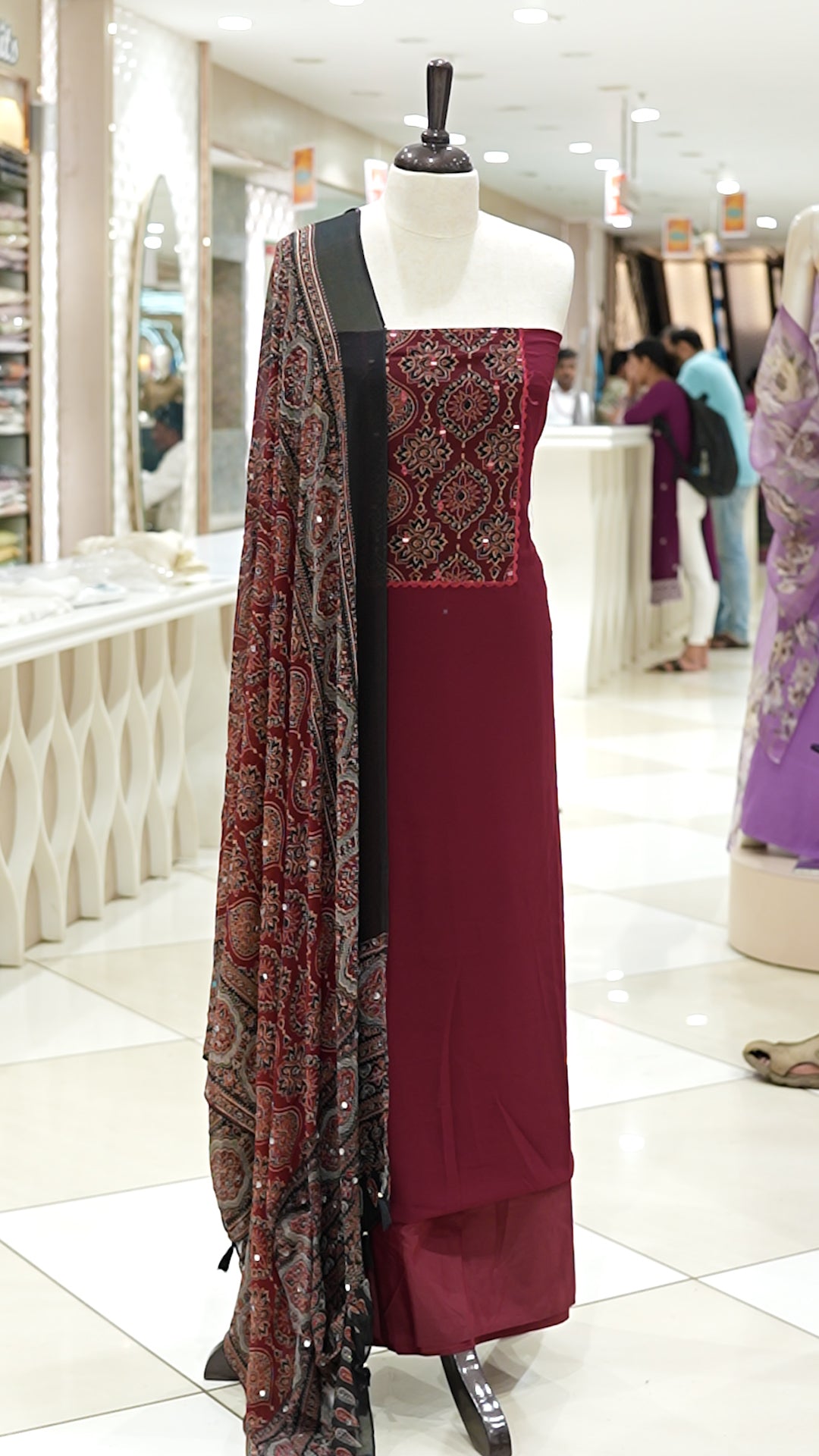 Maroon Georgette salwar material featuring Ajrakh print with mirror work on the yoke, paired with Ajrakh printed dupatta with mirror detailing and plain bottom.