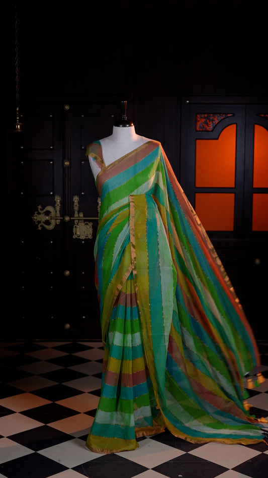 Green Mul Mul cotton saree adorned with subtle gold stripes across the body and finished with a delicate gold zari border.
