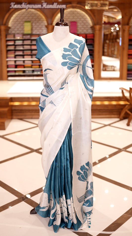 Blue colour semi khadi silk saree featuring bold white floral prints, The highlight is its ivory pallu adorned with elegant blue floral motifs and tassels & Comes with a matching blouse piece.