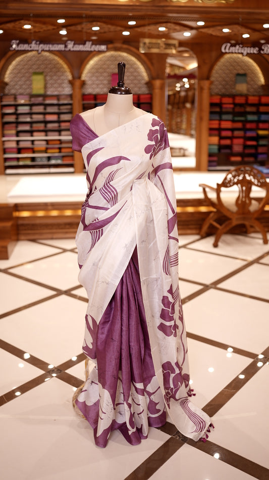 Purple colour semi khadi silk saree featuring bold white floral prints, The highlight is its ivory pallu adorned with elegant purple floral motifs and tassels & Comes with a matching blouse piece.