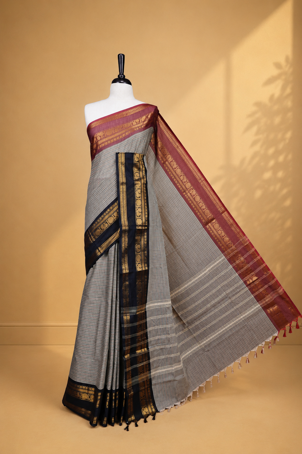 Grey colour chettinad saree featuring Cream colour check pattern on body, complemented by contrast black colour with Gold zari border, paired wih matching blouse piece.