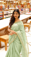 Pista green colour linen tissue saree featuring Floral design with Aari work & contrast simple border, comes with matching blouse piece.