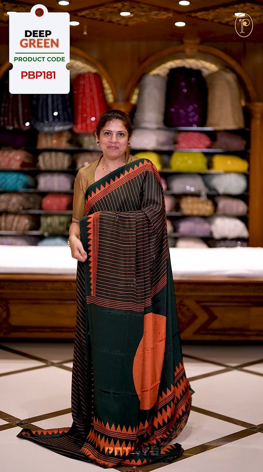 Deep green semi modal saree featuring orange vertical line prints, accented with a contrasting temple border and a bold circular motif on the pallu, paired with a matching printed blouse.
