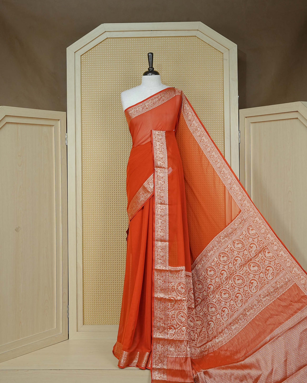 Rust orange colour georgette saree having plain body, peacock & deer gold zari detailed border, comes with matching blouse piece