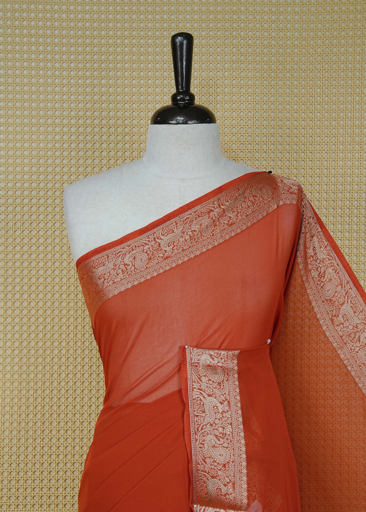 Rust orange colour georgette saree having plain body, peacock & deer gold zari detailed border, comes with matching blouse piece