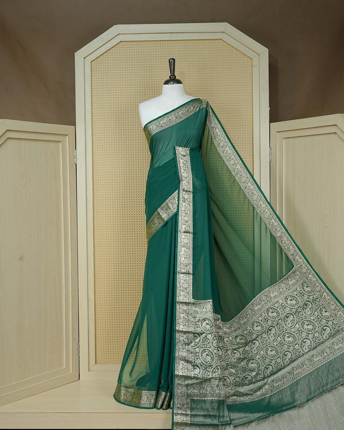 Bottle green colour georgette saree having plain body, peacock & deer gold zari detailed border, comes with matching blouse piece