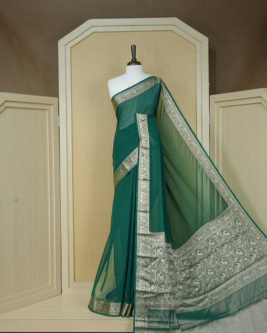 Bottle green colour georgette saree having plain body, peacock & deer gold zari detailed border, comes with matching blouse piece