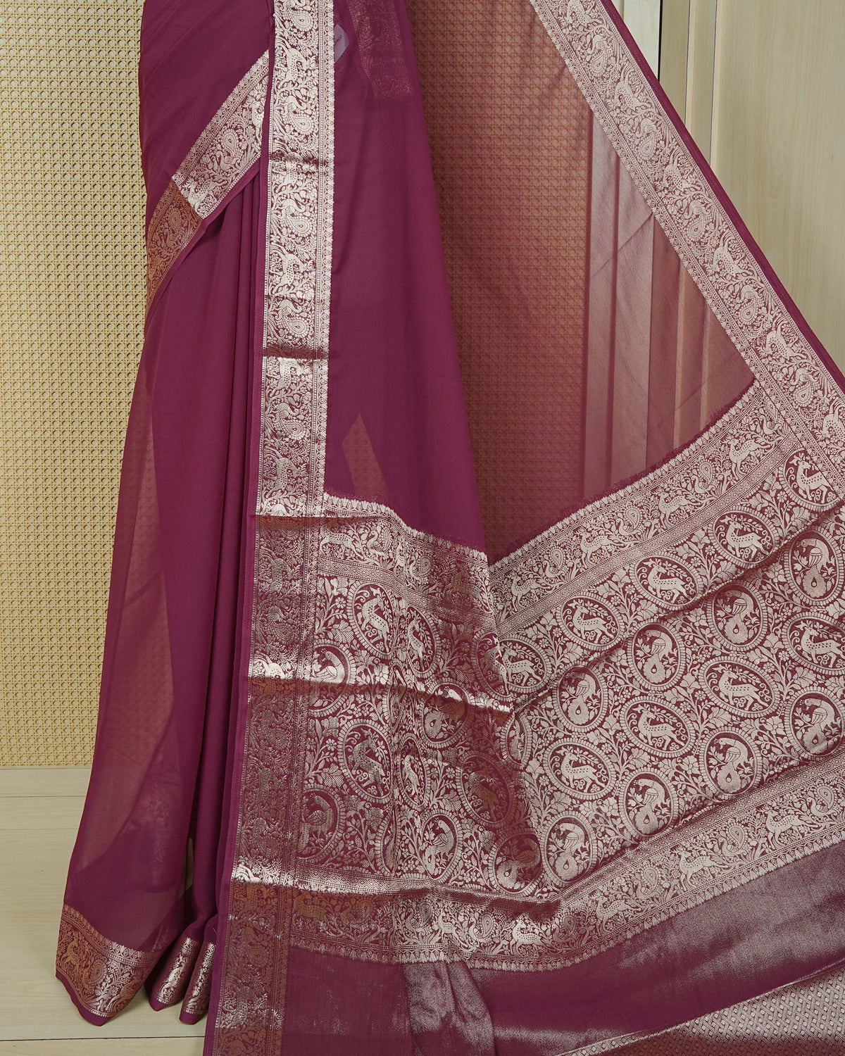 Wine colour georgette saree having plain body, peacock & deer gold zari detailed border, comes with matching blouse piece