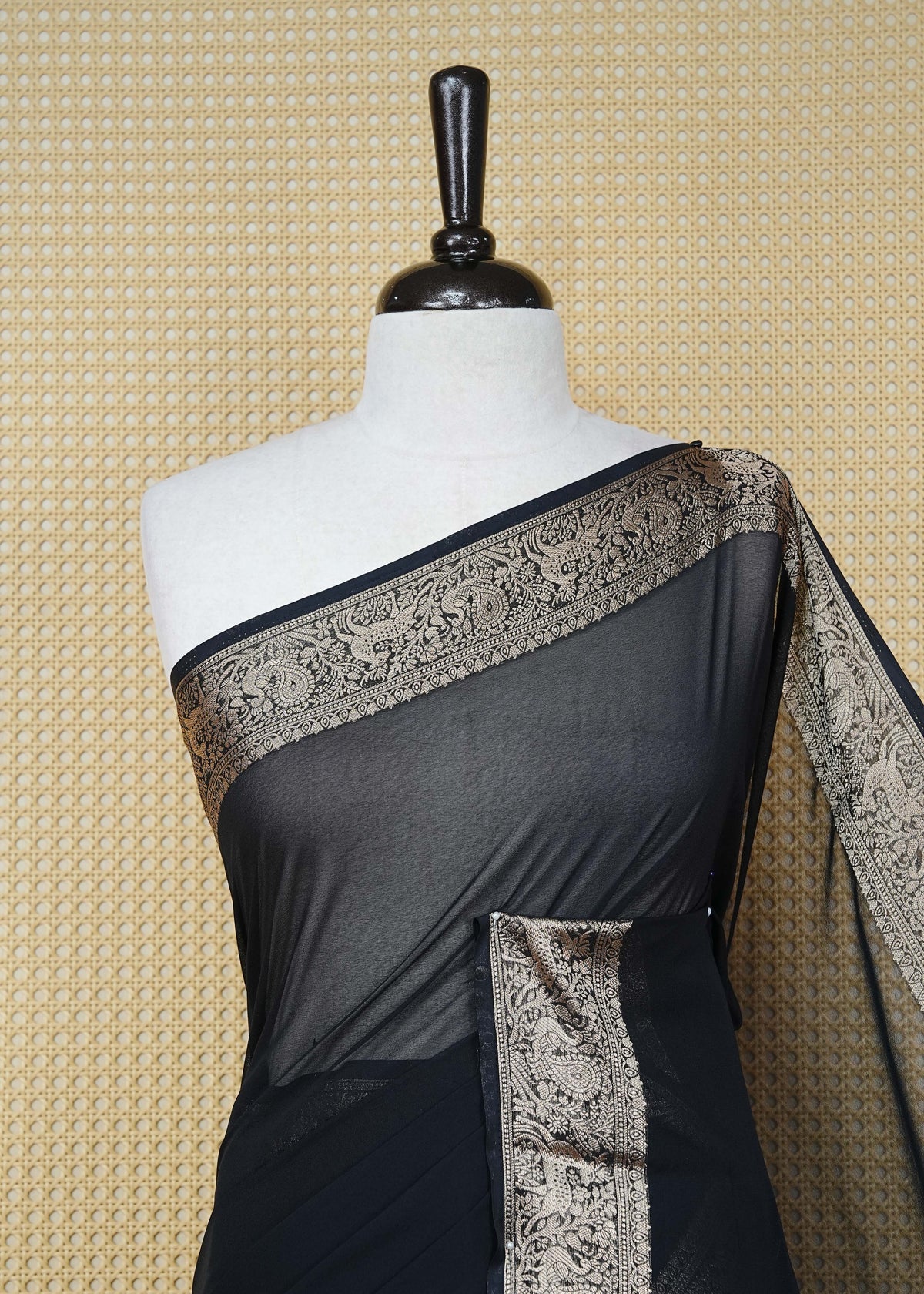 Black colour georgette saree having plain boy, Floral Gold zari detailed pattern border, comes with matching blouse piece