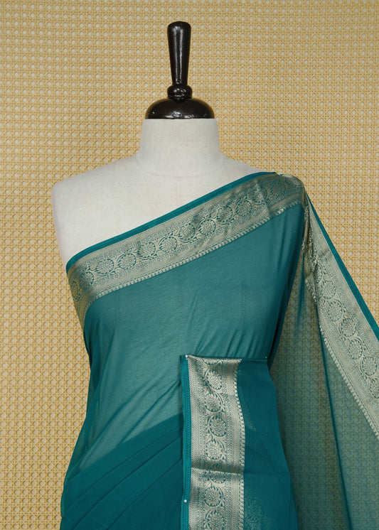 Teal green colour georgette saree having plain boy, Floral Gold zari detailed pattern border, comes with matching blouse piece