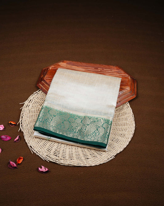 Cream colour Tussar silk saree Featuring Plain body, complemented by Contrast dark green colour gold zari peacock & mango motifs on border, paired with matching blouse piece.