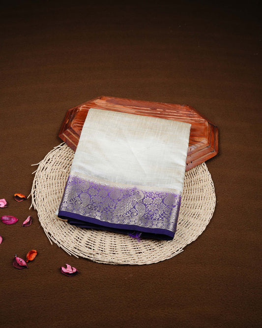 Cream colour Tussar silk saree Featuring Plain body, complemented by Contrast purple colour with gold zari peacock & mango motifs on border, paired with matching blouse piece.