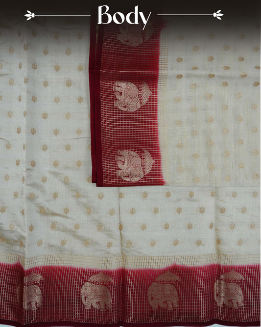 Cream colour Tussar silk saree Featuring buttas on body, complemented by Contrast maroon colour gold zari check pattern with elephant motifs on border, paired with matching blouse piece.