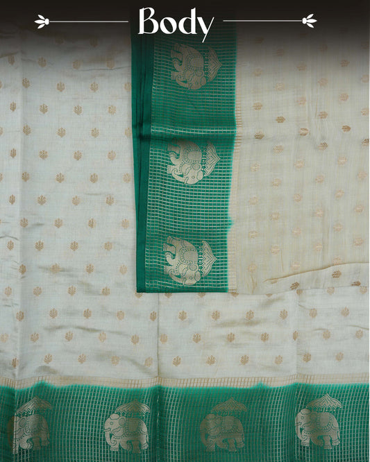 Cream colour Tussar silk saree Featuring buttas on body, complemented by Contrast green colour gold zari check pattern with elephant motifs on border, paired with matching blouse piece.
