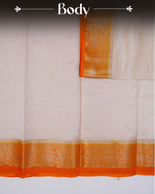 Cream colour Tussar silk saree Featuring Plain body, complemented by Contrast orange colour gold zari elephant & tree motifs on border, paired with matching blouse piece.