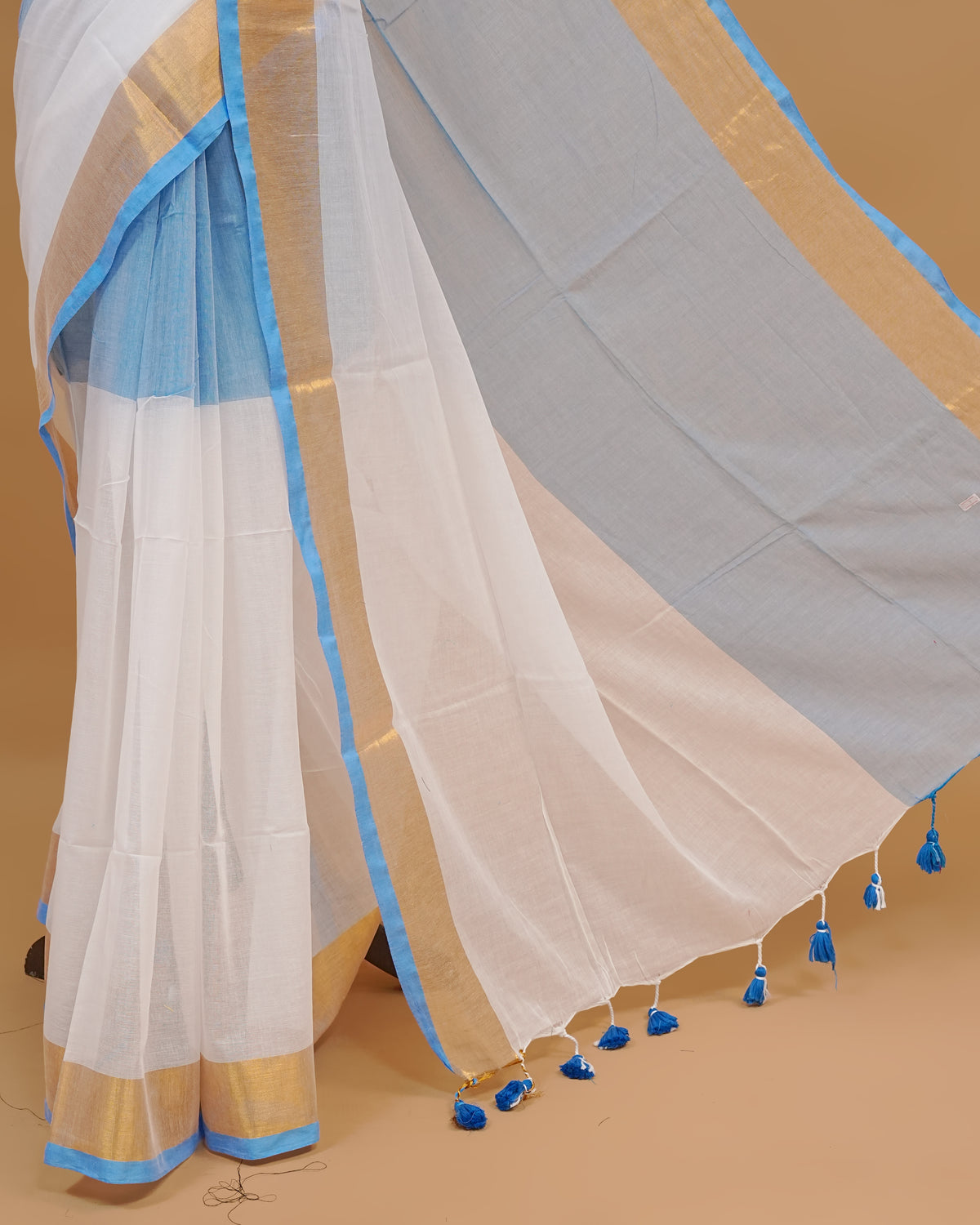 White Colour Mul Cotton Saree Featuring Plain body. With Contrast Gold and Blue Border, pallu comes With Blue Tassels