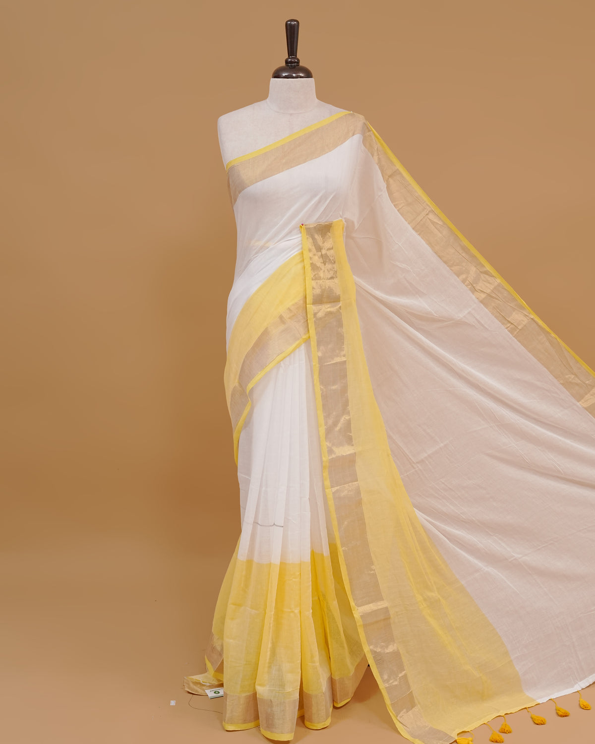 White colour Mul cotton saree featuring Elegant Plain body, complemented by contrast yellow & gold zari border & Tassels.