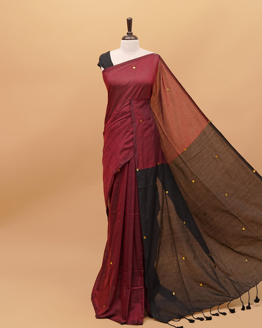 Black and Maroon coloured half and half mul cotton saree featuring elegant sequin detailing on the body, finished with a beautiful pallu adorned with tassels.
