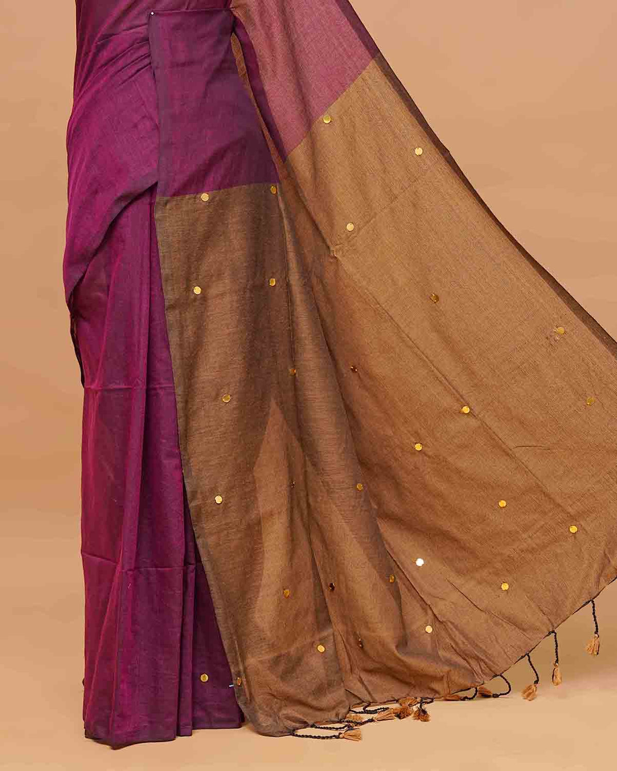 Wine and Kakhi Brown coloured half and half mul cotton saree featuring elegant sequin detailing on the body, finished with a beautiful pallu adorned with tassels.