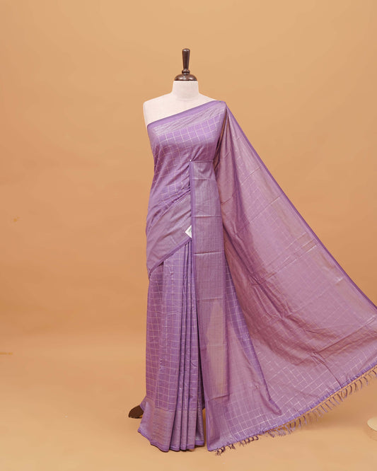 Lavender colour semi silk saree featuring elegant foil checks on the body, complemented by a grand border and a beautiful pallu adorned with tassels.
