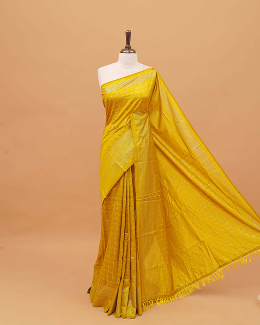 Mustard colour semi silk saree featuring elegant foil checks on the body, complemented by a grand border and a beautiful pallu adorned with tassels.