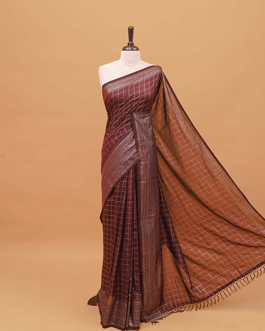 Chocolate brown colour semi silk saree featuring elegant foil checks on the body, complemented by a grand border and a beautiful pallu adorned with tassels.