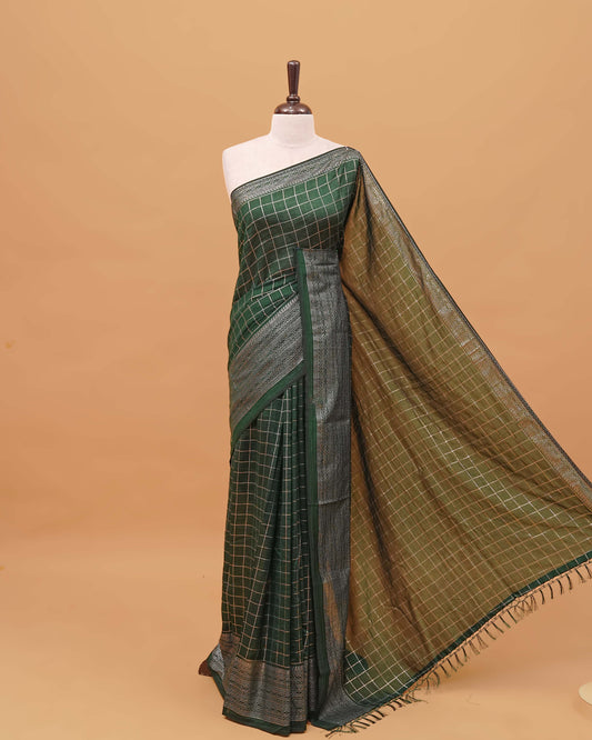 Bottle Green colour semi silk saree featuring elegant foil checks on the body, complemented by a grand border and a beautiful pallu adorned with tassels.