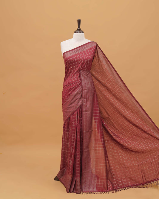 Maroon colour semi silk saree featuring elegant foil checks on the body, complemented by a grand border and a beautiful pallu adorned with tassels.