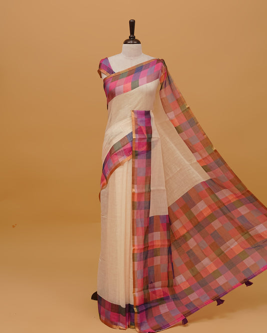 Cream colour Semi linen saree featuring  body, a multicoloured check design with a gold tissue border, and a pallu finished with tassels, paired with a matching blouse piece.