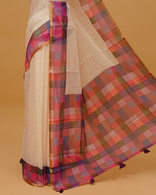 Cream colour Semi linen saree featuring  body, a multicoloured check design with a gold tissue border, and a pallu finished with tassels, paired with a matching blouse piece.