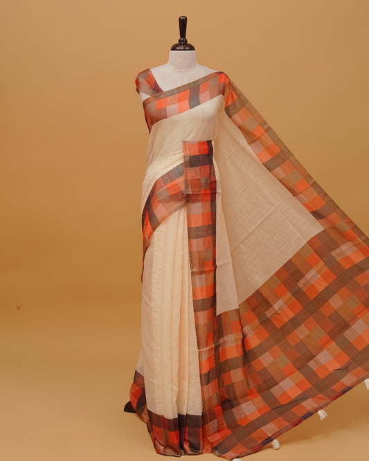 Cream colour Semi linen saree featuring Plain body, a multicoloured check design with a gold tissue border,, and a pallu finished with White tassels, Paired with a matching blouse piece.