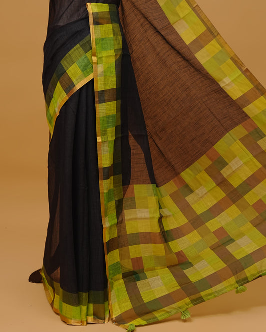 Black colour Semi linen saree featuring a plain body, Multi coloured check design with a Gold tissue simple border, and a pallu finished with Green tassels, Paired with a matching blouse piece.