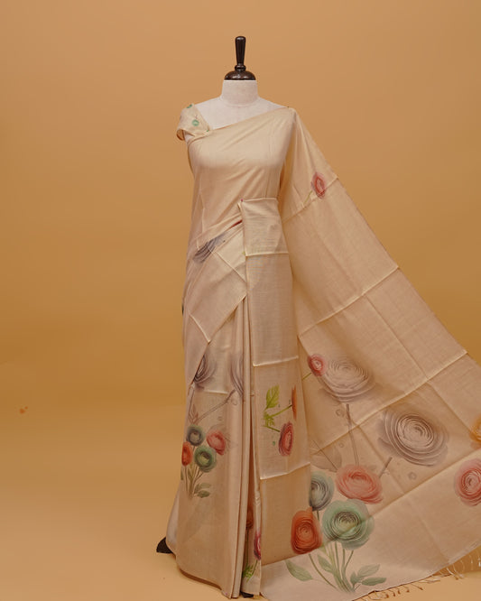 Cream colour Semi Tissue saree featuring Floral Motifs on body, a Gold Simple border, a pallu finished with tassels, paired with a matching blouse piece.