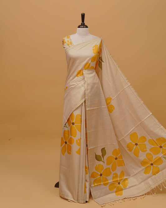Cream colour Semi Tissue saree featuring  Yellow colour Floral Motifs on body, a Threaded border, a pallu finished with tassels, paired with a matching blouse piece.