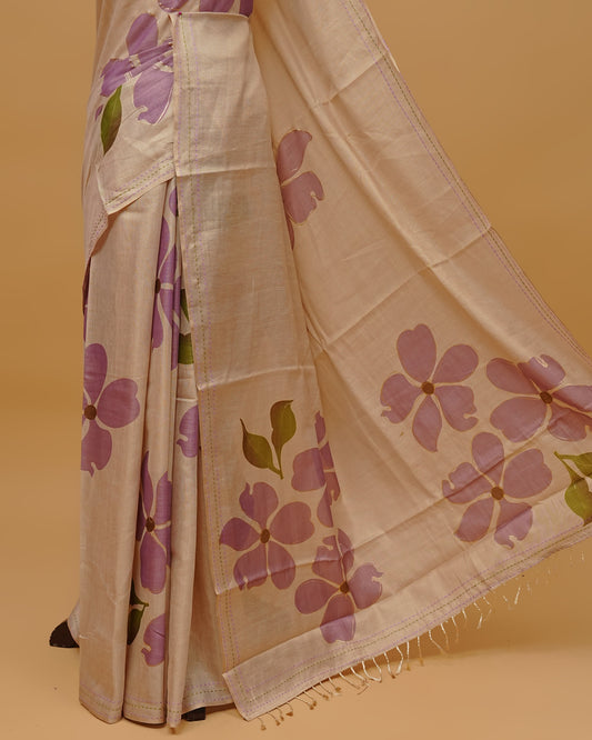 Cream colour Semi Tissue saree featuring  Lavender colour Floral Motifs on body, a Threaded border & pallu finished with tassels, paired with a matching blouse piece.