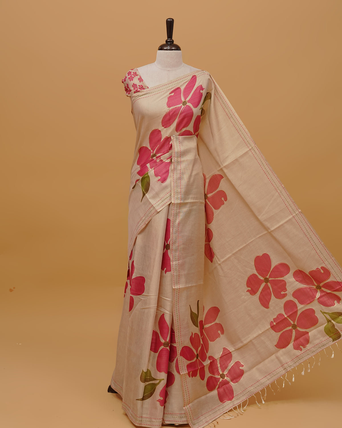 Cream colour Semi Tissue saree featuring Pink Colour Floral Motifs on body, a Threaded border & a pallu finished with tassels, paired with a matching blouse piece.