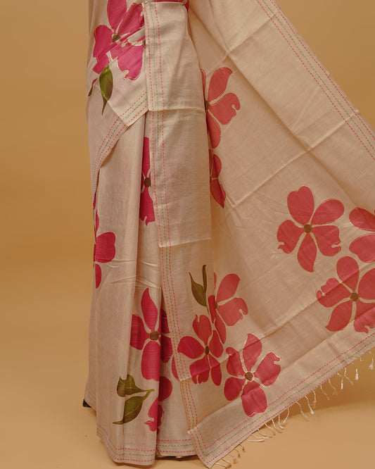 Cream colour Semi Tissue saree featuring Pink Colour Floral Motifs on body, a Threaded border & a pallu finished with tassels, paired with a matching blouse piece.