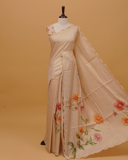 Cream colour Semi Tissue saree featuring Floral Motifs and Mirror Work on the body, a Scallop border, and a pallu finished with tassels, paired with a matching blouse piece.