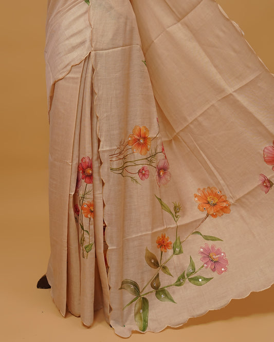Cream colour Semi Tissue saree featuring Floral Motifs and Mirror Work on the body, a Scallop border, and a pallu finished with tassels, paired with a matching blouse piece.