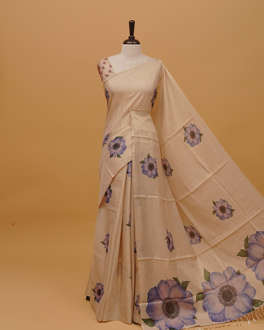 Cream colour Semi Tissue saree featuring Light Purple Floral Motifs on body, a Gold Simple Border & pallu finished with tassels, paired with a matching blouse piece.